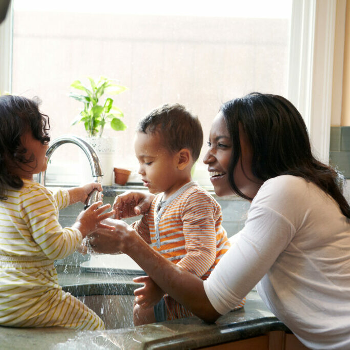 Mother and children (18-23 months) splashing water
