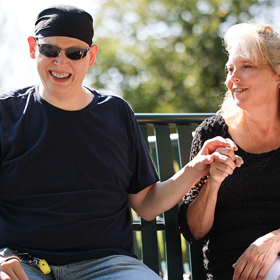 Blind, adult male smiling and signing into the hand of his service provider.